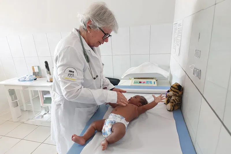 Médica pediatra realizando exame clínico em um bebê no CER III da Pestalozzi Guarapari.